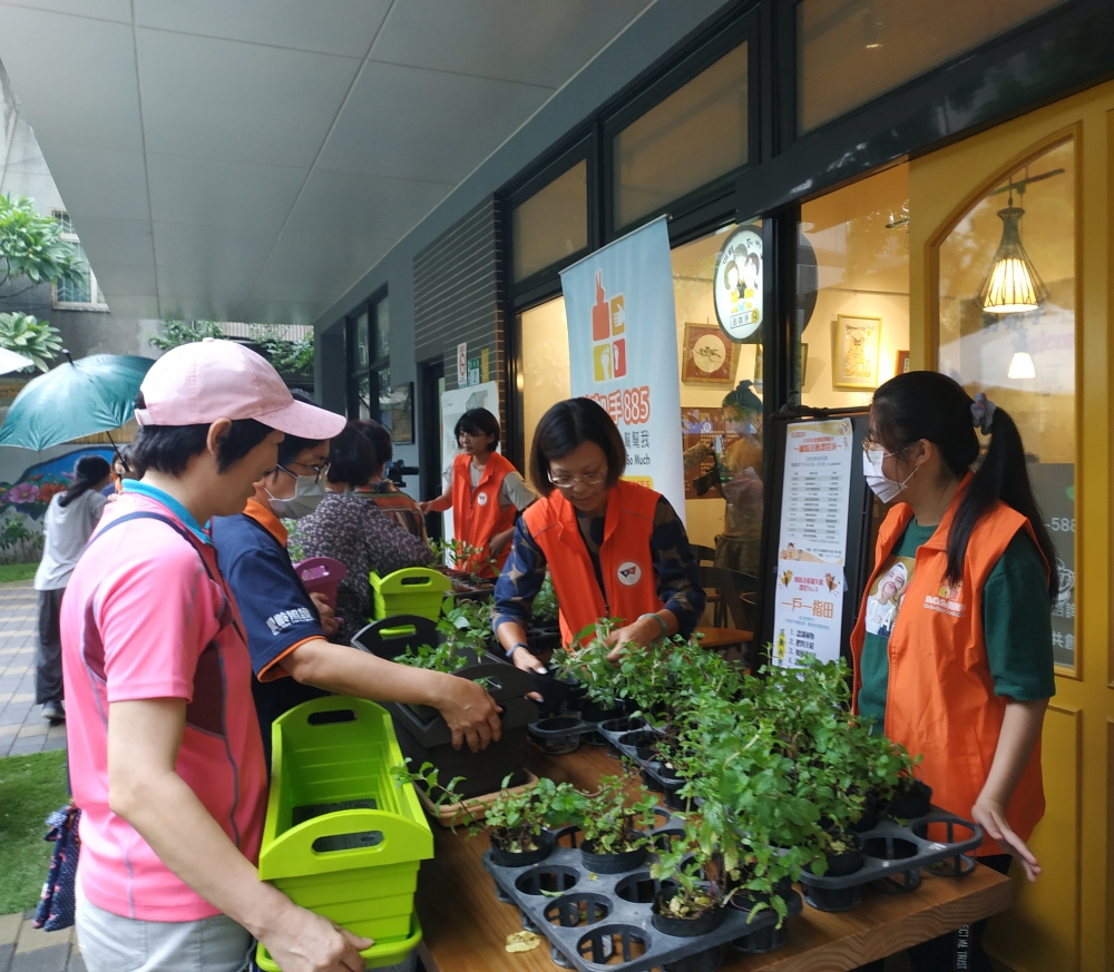 志工至銀光咖啡館推廣一戶一指田活動，帶領長者一起將菜苗種進菜槽裡。